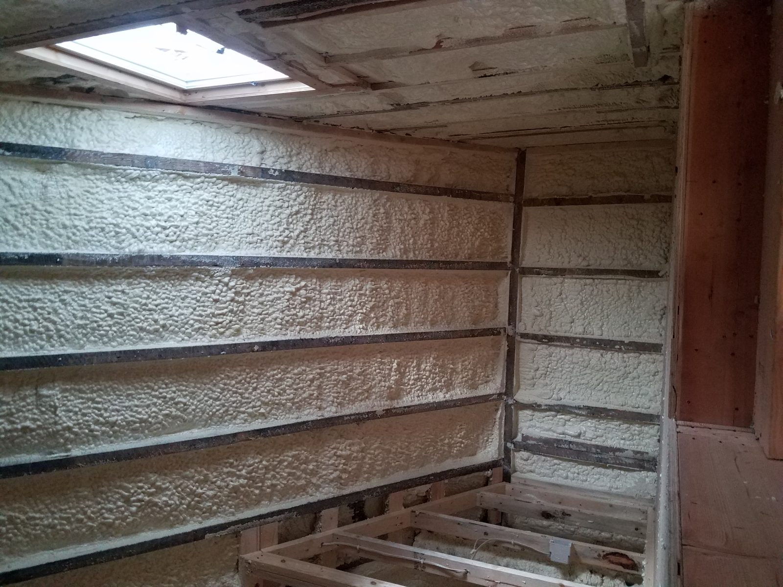 Closed-cell spray foam being applied to a steel roof deck